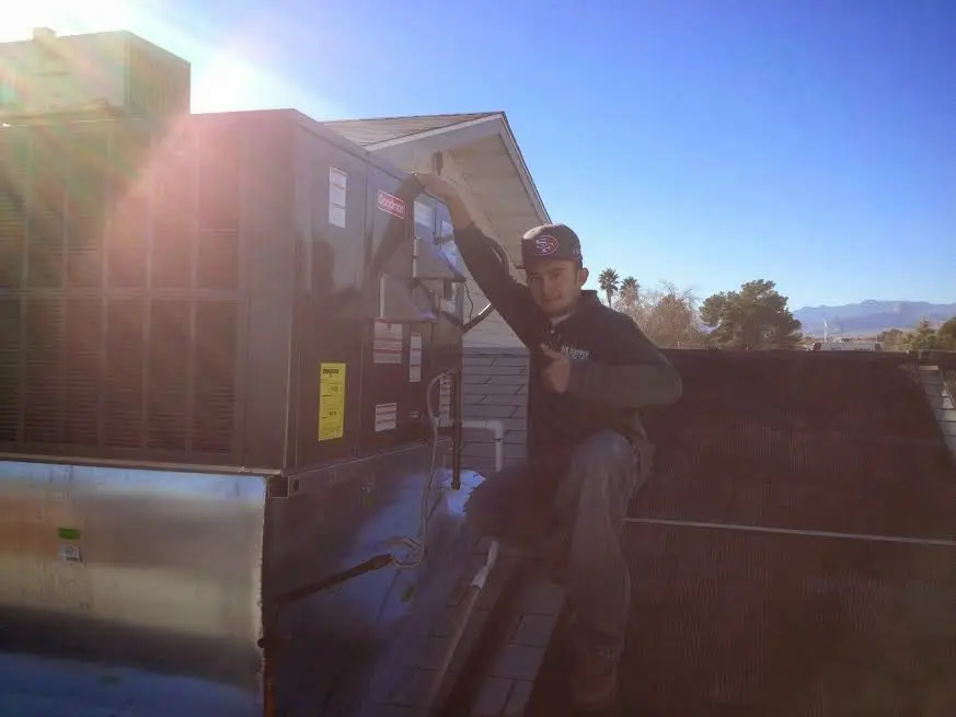 HVAC technician performing AC Tune-Up on a rooftop unit in Massena